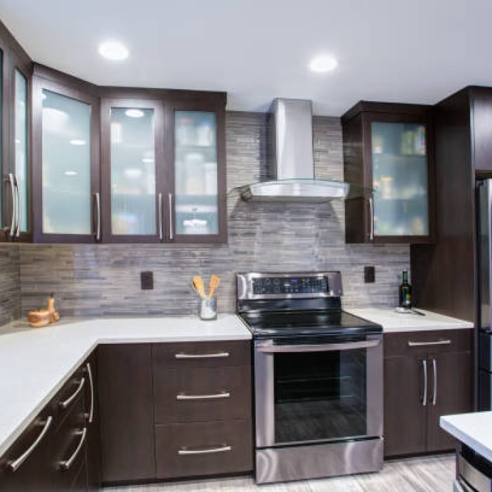 Updated contemporary kitchen room interior with white counters and dark wood cabinets fitted with luxury stainless steel appliances.